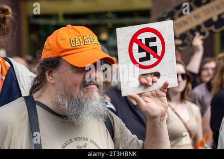 Homme barbu gris tenant un petit panneau en carton avec une croix swastika à Me emme vaikene! Manifestation anti-rasicme à Helsinki, Finlande Banque D'Images