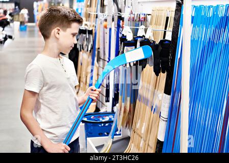 Garçon avec crosse de hockey dans un magasin d'articles de sport Banque D'Images