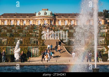 Les visiteurs apprécient l'élégante façade et les jardins en terrasses du palais de Sanssouci à Potsdam, en Allemagne, par une journée claire d'automne Banque D'Images