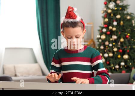 Mignon petit garçon jouant synthétiseur à la maison le soir de Noël Banque D'Images