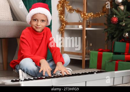 Mignon petit garçon jouant synthétiseur à la maison le soir de Noël Banque D'Images