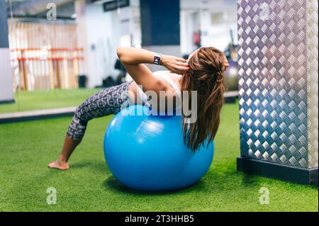 Femme faisant de la gymnastique sur un ballon en plastique Banque D'Images