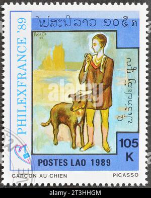 Timbre postal annulé imprimé par le Laos, qui montre le tableau chien avec garçon, Pablo Picasso, vers 1989. Banque D'Images