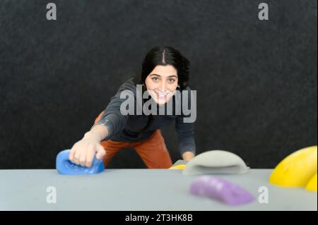 Vue de la femme grimpeuse professionnelle grimpant sur le mur pratique intérieur, bloc Banque D'Images