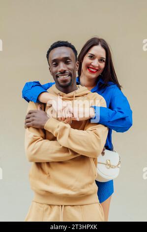 Portrait d'un couple interracial heureux en vêtements décontractés Jeune brune d'apparence européenne embrasse son petit ami afro-américain Banque D'Images