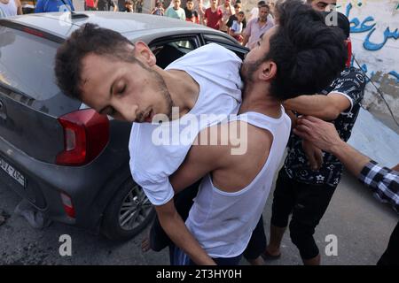 Rafah, Gaza. 25 octobre 2023. Un homme transporte un blessé lorsqu’un supermarché a été touché par une frappe israélienne sur le camp de réfugiés de Rafah, dans le Sud de la bande de Gaza, le mercredi 25 octobre 2023. Le nombre de morts des frappes israéliennes sur la bande de Gaza a augmenté à près de 7 000, a déclaré le ministère palestinien de la Santé. Photo par Ismael Mohamad/UPI. Crédit : UPI/Alamy Live News Banque D'Images