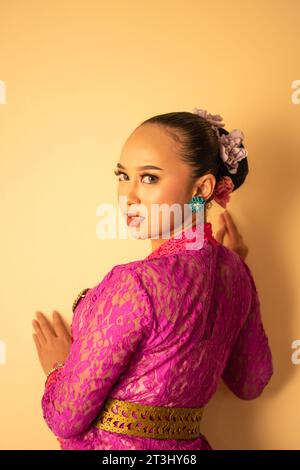 Mère balinaise portant une robe rose appelée kebaya et du maquillage avant de prier dans le temple Banque D'Images