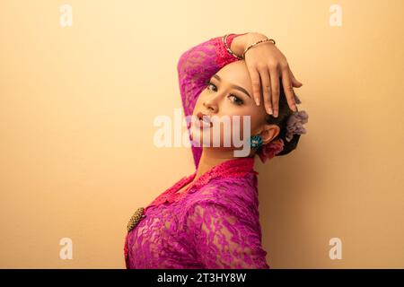 Mère balinaise portant une robe rose appelée kebaya et du maquillage avant de prier dans le temple Banque D'Images