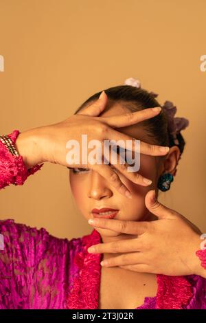 Portrait de femme balinaise avec robe rose pose avec les mains sur le visage à l'intérieur de la pièce Banque D'Images