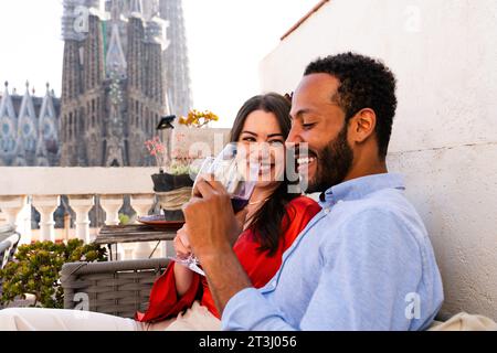 Multiracial beau couple heureux d'amoureux datant sur le balcon sur le toit à la Sagrada Familia, Barcelone - personnes multiethniques ayant un apéritif romantique sur Banque D'Images