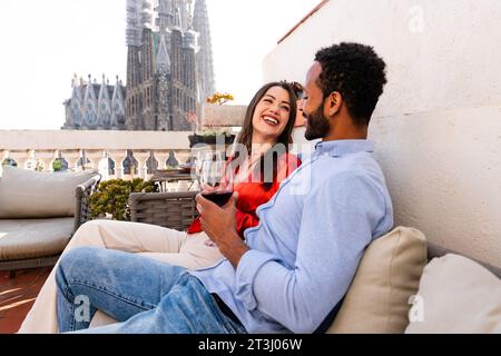 Multiracial beau couple heureux d'amoureux datant sur le balcon sur le toit à la Sagrada Familia, Barcelone - personnes multiethniques ayant un apéritif romantique sur Banque D'Images