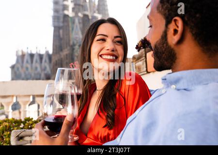 Multiracial beau couple heureux d'amoureux datant sur le balcon sur le toit à la Sagrada Familia, Barcelone - personnes multiethniques ayant un apéritif romantique sur Banque D'Images