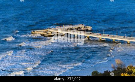 Prélassez-vous dans la sérénité baignée de soleil de la jetée de Kołobrzeg, telle que capturée par cette photo de drone. La vaste promenade en bois s'étend dans la Baltique azur. Banque D'Images
