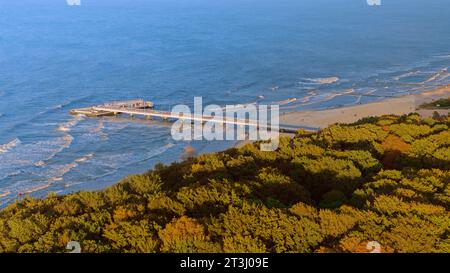 Prélassez-vous dans la sérénité baignée de soleil de la jetée de Kołobrzeg, telle que capturée par cette photo de drone. La vaste promenade en bois s'étend dans la Baltique azur. Banque D'Images