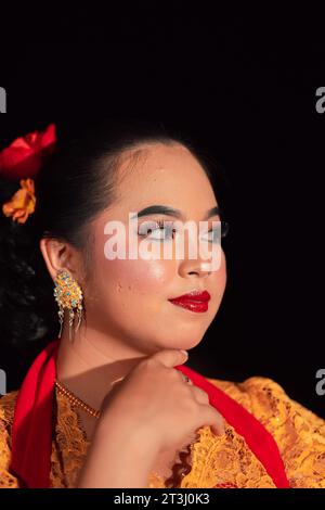 Beau visage d'une femme asiatique aux lèvres rouges et maquillage en costume de danse traditionnelle indonésienne après le spectacle de danse sur scène Banque D'Images