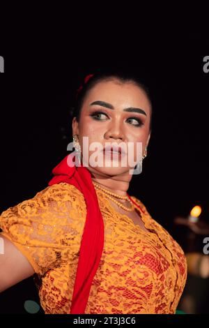 Femme javanaise dans une robe orange traditionnelle tout en portant le maquillage et une écharpe rouge à un festival de danse en Indonésie Banque D'Images