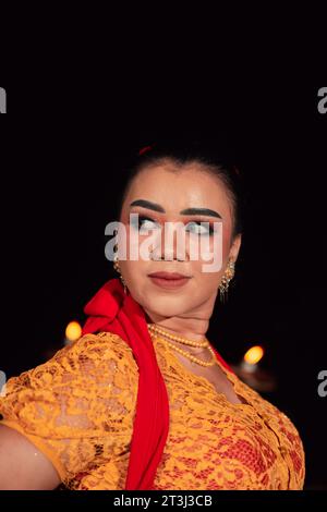 Femme javanaise dans une robe orange traditionnelle tout en portant le maquillage et une écharpe rouge à un festival de danse en Indonésie Banque D'Images