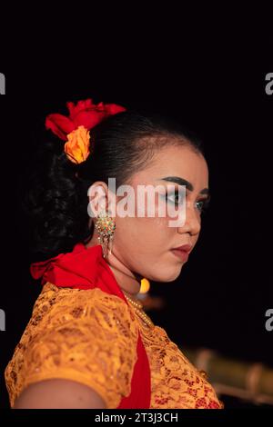 Femme javanaise dans une robe orange traditionnelle tout en portant le maquillage et une écharpe rouge à un festival de danse en Indonésie Banque D'Images