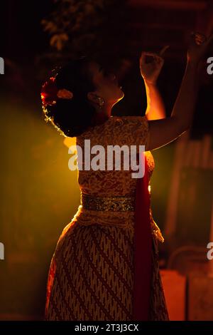 Les femmes balinaises portant des vêtements culturels tout en posant devant la lumière avec des mouvements de danse sur leur corps Banque D'Images