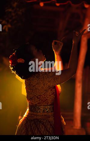 Les femmes balinaises portant des vêtements culturels tout en posant devant la lumière avec des mouvements de danse sur leur corps Banque D'Images