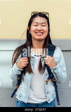 Portrait de femme asiatique souriante avec sac à dos dans la rue Banque D'Images