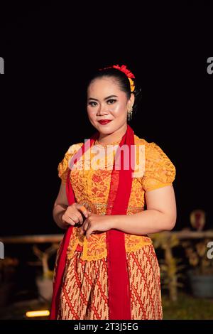 Mignonne femme indonésienne avec des lèvres rouges et une écharpe rouge portant une robe traditionnelle sundanaise appelée kebaya à l'intérieur du festival de danse Banque D'Images