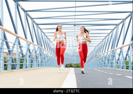 Deux femmes athlétiques en vêtements de sport font du jogging sur un pont Banque D'Images