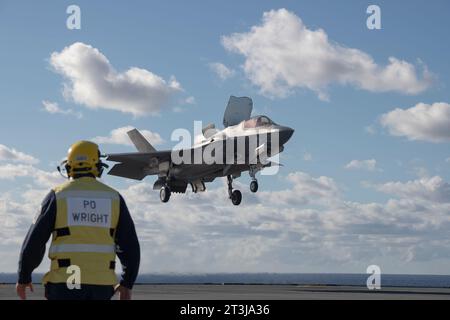 Patuxent River, États-Unis. 24 octobre 2023. Un pilote d'avion de la Royal Navy regarde un chasseur furtif F-35B Lightning II du corps des Marines américain effectuer un atterrissage vertical roulant embarqué sur le pont d'envol du porte-avions de classe Queen Elizabeth de la Royal Navy HMS Prince of Wales au cours des essais en vol de phase de développement 3, octobre 24, 2023 au large des côtes du Maryland, États-Unis. Crédit : Michael Jackson/États-Unis Navy photo/Alamy Live News Banque D'Images