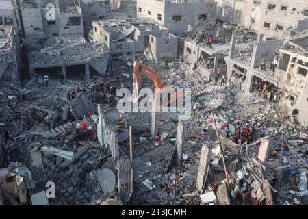 Gaza, Palestine. 25 octobre 2023. Une excavatrice déblaie les décombres alors que les gens recherchent les survivants et les corps des victimes à travers des bâtiments détruits lors des bombardements israéliens, à Khan Yunis, dans le sud de la bande de Gaza. Crédit : SOPA Images Limited/Alamy Live News Banque D'Images