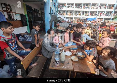 Gaza, Palestine. 25 octobre 2023. Des enfants palestiniens vus autour de la table dans la cour de récréation d’une école gérée par l’Office de secours et de travaux des Nations Unies pour les réfugiés de Palestine (UNRWA) qui a été transformée en abri pour les Palestiniens déplacés à Khan Yunis, dans le sud de la bande de Gaza. Crédit : SOPA Images Limited/Alamy Live News Banque D'Images