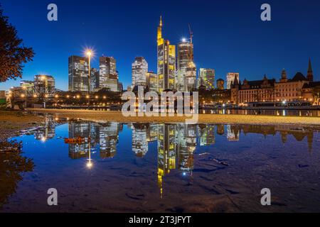 Die leuchtende Frankfurter Skyline am Abend Die leuchtende Frankfurter Bankenskyline spiegelt sich am Abend zur Blauen Stunde in einer Regenpfütze am Mainufer. Frankfurt am main Mainufer Hessen Deutschland *** l'horizon brillant de Francfort dans la soirée l'horizon brillant de la banque de Francfort se reflète dans une flaque de pluie dans la soirée à l'heure bleue Frankfurt am main Mainufer Hesse Allemagne 2023-10-25 ffm Skyline 07 crédit : Imago/Alamy Live News Banque D'Images