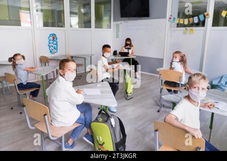 Enfants enseignants portant des masques médicaux pendant la pandémie Banque D'Images