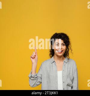 Femme à tir moyen pointant vers le haut Banque D'Images