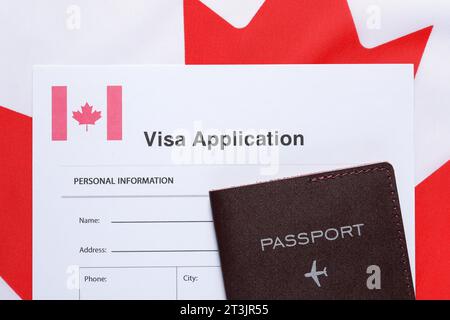 Immigration au Canada. Formulaire de demande de visa et passeport sur drapeau, vue de dessus Banque D'Images