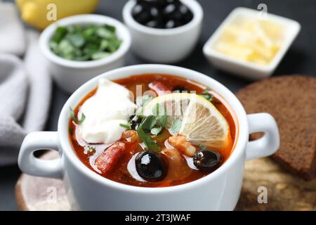 Soupe solyanka à la viande avec saucisses, olives et légumes dans un bol servi sur table, gros plan Banque D'Images