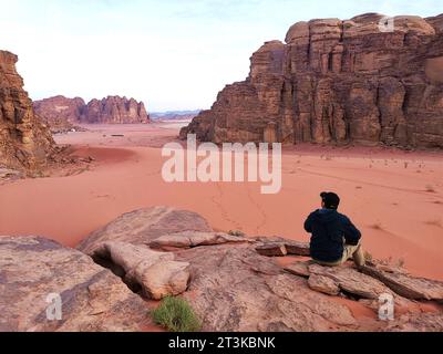 Un homme est assis sur un rocher dans le désert de Wadi Rum en Jordanie où Mars ressemble le plus au terrain sur terre. Banque D'Images