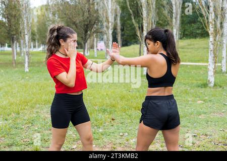 Deux jeunes boxeuses multiethniques s'entraînant en plein air. Entraînement de boxe et de poinçonnage. Banque D'Images
