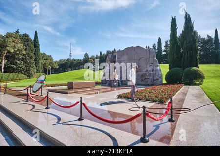 Un jardinier arrose des fleurs sur la tombe et la statue de l'ancien président Heydar Aliyev. Au cimetière public de la statue de l'allée d'honneur et du parc commémoratif i. Banque D'Images