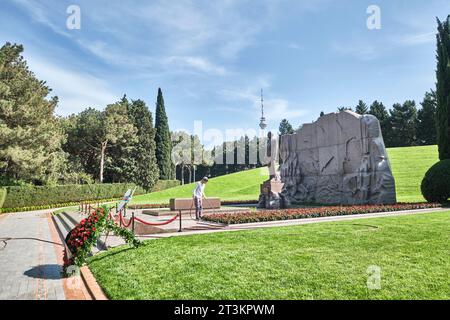 Un jardinier arrose des fleurs sur la tombe et la statue de l'ancien président Heydar Aliyev. Au cimetière public de la statue de l'allée d'honneur et du parc commémoratif i. Banque D'Images
