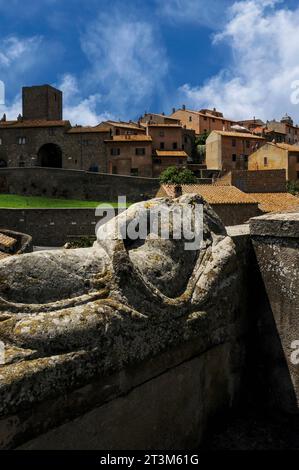 Effigie sans tête couchée sur le couvercle de sarcophage étrusque antique à Tuscania, Latium, Italie, avec la vieille ville de Tuscania se levant derrière. Tuscania était autrefois l'ancienne ville étrusque de Tuscana. Il se trouve à environ 80 km (50 miles) au nord-ouest de Rome. Banque D'Images