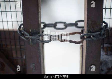 Chaîne à la porte. Chaîne en acier sur clôture. Portes fermées en hiver. Maillons de chaîne. Banque D'Images