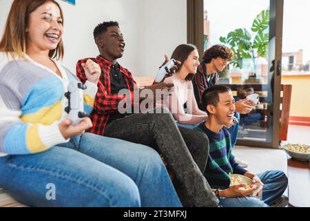 Jeunes amis multiraciaux s'amusant à jouer à des jeux vidéo à la maison - concept de style de vie de génération z et de vacances d'hiver - Focus sur le visage de gars asiatique Banque D'Images