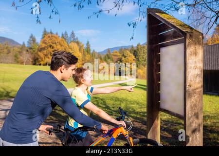 Cycliste femme et homme regardant le panneau d'information dans la nature Banque D'Images