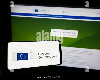 Personne détenant un téléphone portable avec le logo de l'institution de l'UE Commission européenne (ce) devant la page Web. Concentrez-vous sur l'affichage du téléphone. Banque D'Images