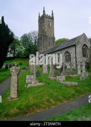 Vue au nord-ouest de l'église St Nonna, Altarnun, Cornouailles, Angleterre, Royaume-Uni, avec une ancienne croix-tête re-érigée sur un puits moderne par la porte du cimetière se. Banque D'Images