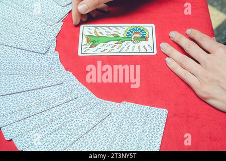 vue de dessus d'une femme lecteur de tarot caucasien méconnaissable, assise commençant la lecture thérapeutique, prenant et retournant la carte du pont et la plaçant Banque D'Images