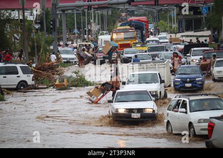 Acapulco, Mexique. 25 octobre 2023. Les voitures traversent une rue inondée après que l'ouragan 'Otis' est passé au-dessus de la région. « Otis » a touché terre tôt mercredi en tant qu'ouragan de catégorie 5 extrêmement dangereux avec des vents soutenus de près de 270 kilomètres par heure et des rafales allant jusqu'à 330 kilomètres par heure. Crédit : eduardo guerrero/dpa/Alamy Live News Banque D'Images