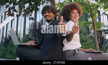 Collègues multiraciaux d'affaires travaillant avec des ordinateurs portables dans la ville homme indien homme d'affaires arabe avec femme d'affaires afro-américaine en plein air dactylographiant Banque D'Images