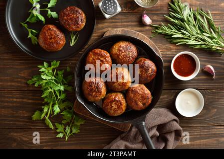 Porc haché maison et côtelettes de bœuf dans une poêle en fonte sur fond en bois. Vue de dessus, pose à plat Banque D'Images