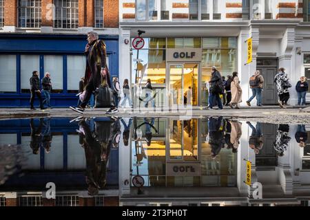 Londres, 26 octobre 2023. Météo au Royaume-Uni – les gens se reflètent dans une flaque d'eau au bord de la route à Beak Street près de Carnaby Street. Les prévisions sont pour des conditions plus sèches avant un week-end probablement humide. Crédit : Stephen Chung / Alamy Live News Banque D'Images